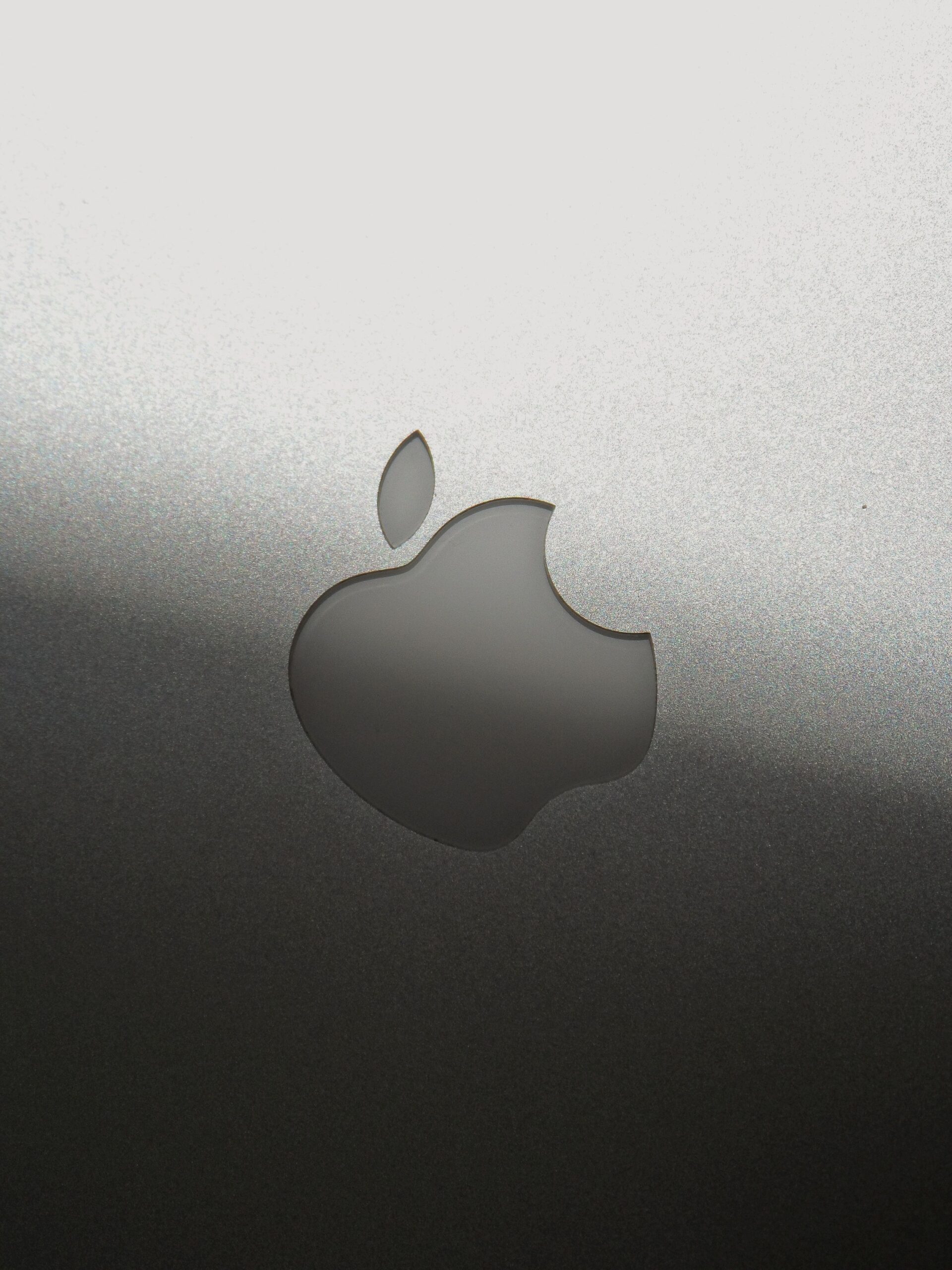 Close-up of a sleek silver Apple logo on a metallic surface, showcasing branding elegance.